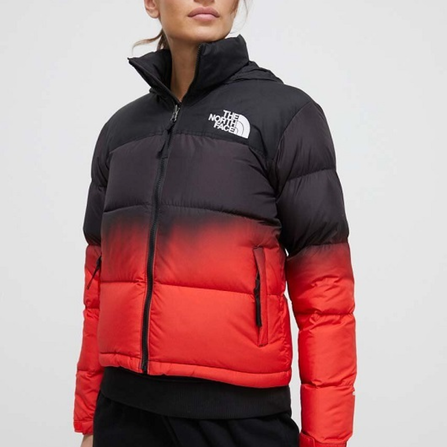 Geacă de iarnă scurtă The North Face în degrade, combinând negrul cu o nuanță aprinsă de roșu. Model cu umplutură din puf natural și pene 