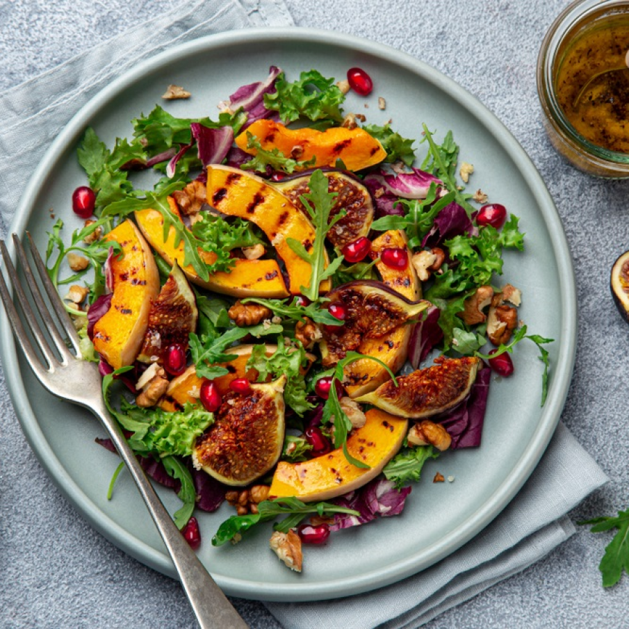 O salată delicioasă pe post de aperitiv, cu arome bogate de toamnă, obținută din: rucola și alte frunze de salate, dovleac copt, smochine, nuci și semințe de rodie